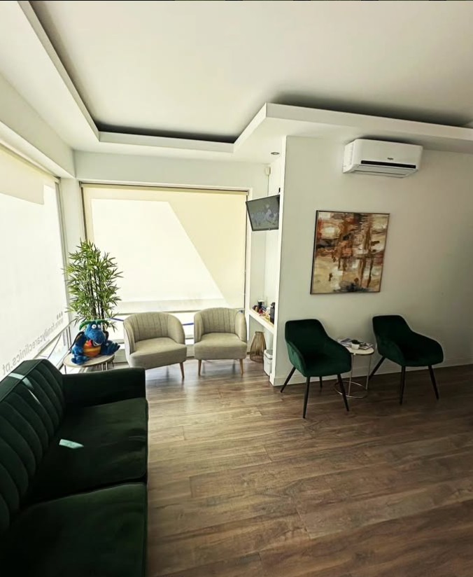 Sala de espera ampla com sofá verde e piso de madeira